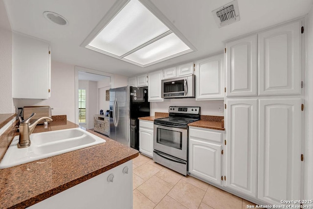 kitchen featuring white cabinetry, sink, light tile patterned floors, and stainless steel appliances