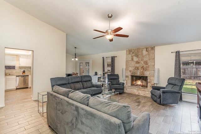 living room featuring lofted ceiling, a fireplace, and ceiling fan