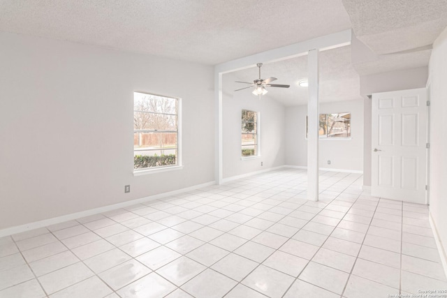 empty room featuring light tile patterned flooring, ceiling fan, lofted ceiling, and a textured ceiling