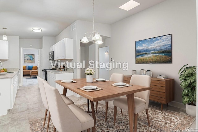 dining area with sink, a notable chandelier, and a skylight