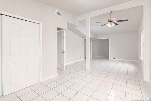 tiled empty room featuring vaulted ceiling, a textured ceiling, and ceiling fan