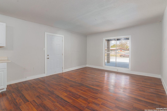 spare room featuring a textured ceiling and dark hardwood / wood-style flooring