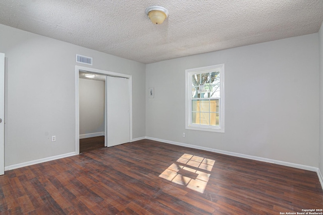 spare room with dark hardwood / wood-style floors and a textured ceiling