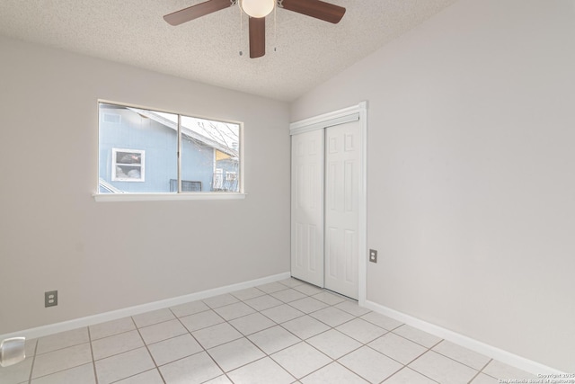 interior space with ceiling fan, vaulted ceiling, a textured ceiling, and light tile patterned floors