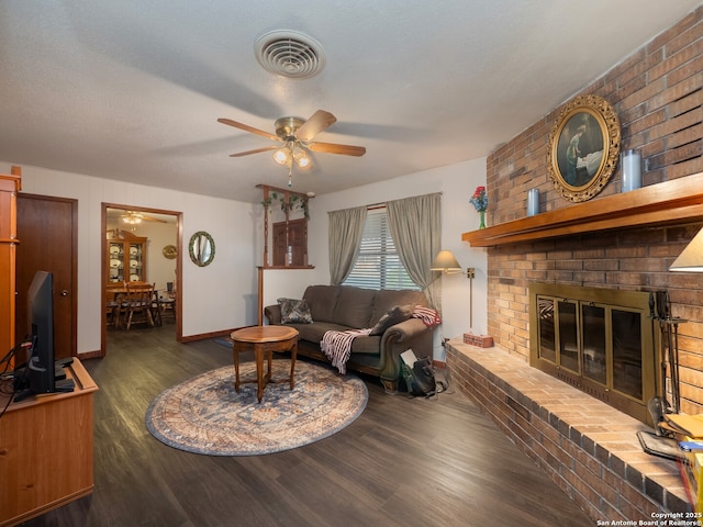 living room with a brick fireplace, dark wood-type flooring, and ceiling fan