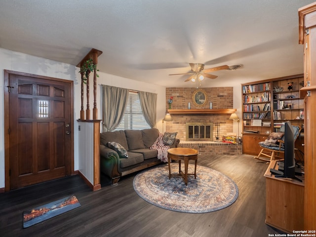 living room featuring ceiling fan, dark hardwood / wood-style floors, and a fireplace