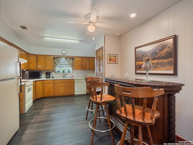 kitchen with dark hardwood / wood-style flooring, sink, white appliances, and ceiling fan