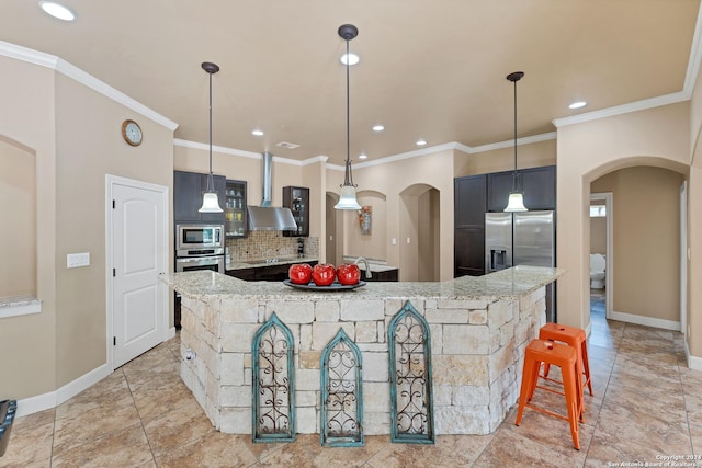 kitchen with light stone countertops, a large island, wall chimney range hood, and appliances with stainless steel finishes