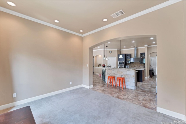 kitchen featuring pendant lighting, a kitchen bar, a center island, light carpet, and wall chimney range hood