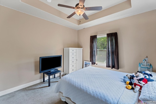 carpeted bedroom featuring ceiling fan and a tray ceiling