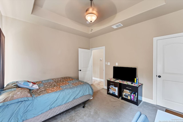 bedroom with ceiling fan, a raised ceiling, and carpet floors