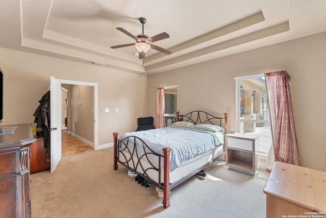 carpeted bedroom featuring ceiling fan and a tray ceiling