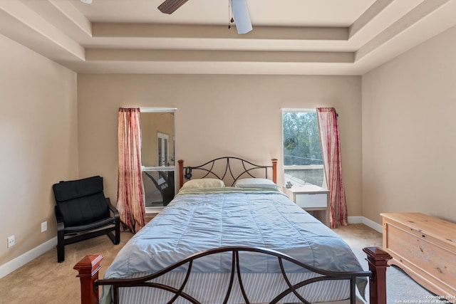 bedroom with light carpet, a raised ceiling, and ceiling fan