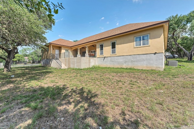 back of property featuring cooling unit and a lawn