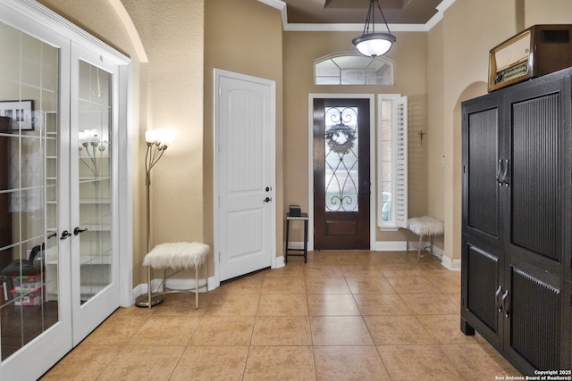 tiled foyer entrance featuring french doors, ornamental molding, and a high ceiling