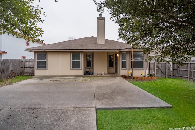 rear view of property featuring a patio area and a lawn