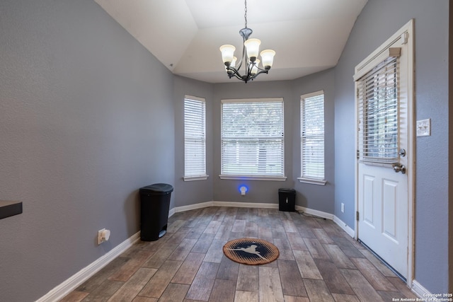 unfurnished dining area with a notable chandelier, vaulted ceiling, and hardwood / wood-style floors