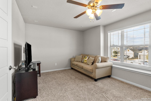 carpeted living room featuring ceiling fan and a textured ceiling