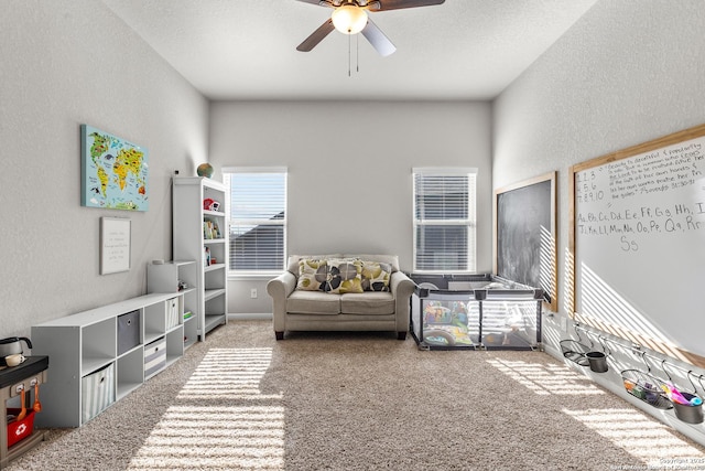 recreation room featuring ceiling fan, carpet floors, and a textured ceiling