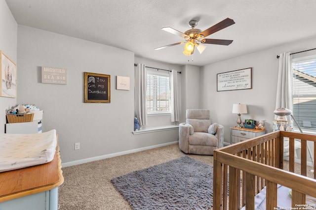 bedroom featuring ceiling fan, a crib, a textured ceiling, and carpet flooring