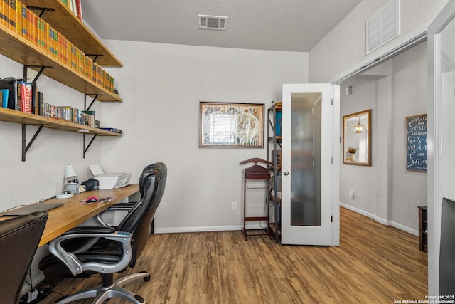 home office featuring wood-type flooring, a textured ceiling, and french doors