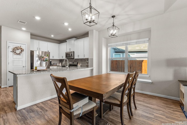 dining room with dark hardwood / wood-style flooring, sink, and a notable chandelier