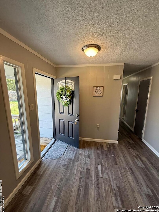 foyer entrance with crown molding, dark wood-type flooring, and a textured ceiling