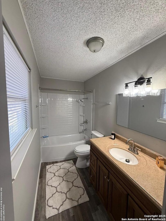 full bathroom featuring vanity, wood-type flooring, a textured ceiling, tiled shower / bath, and toilet