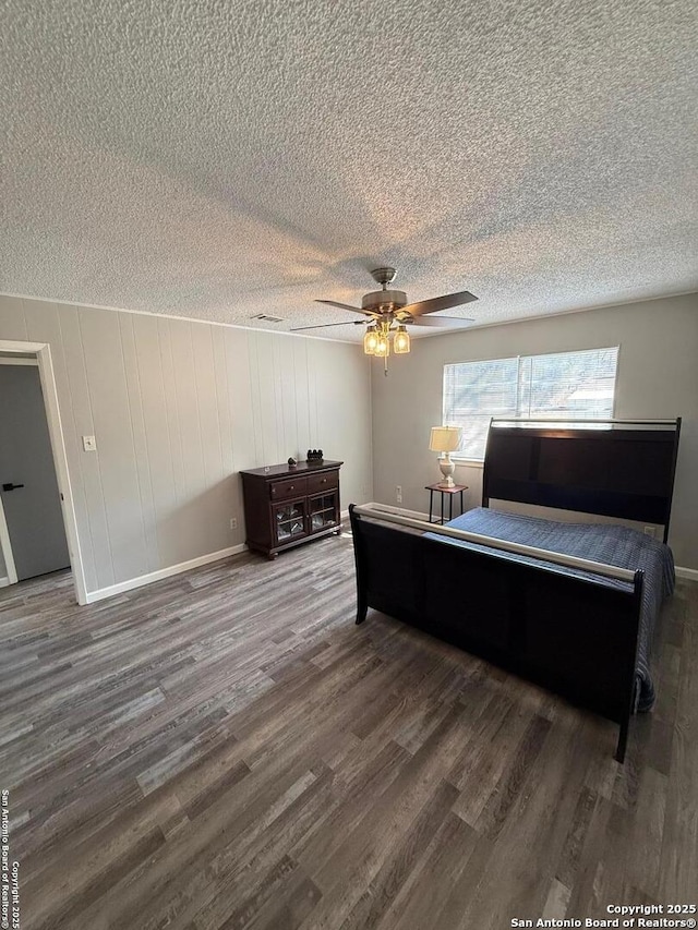 bedroom with ceiling fan, dark wood-type flooring, and a textured ceiling