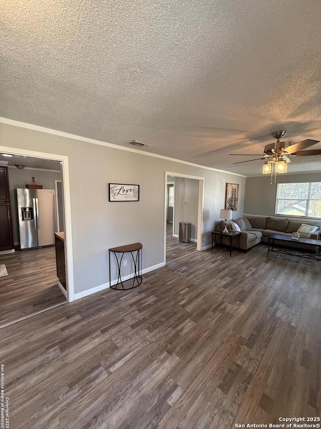 unfurnished living room featuring dark wood-type flooring, ceiling fan, ornamental molding, and a textured ceiling