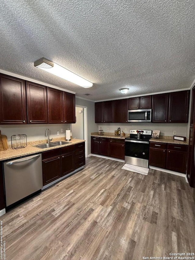 kitchen with stainless steel appliances, wood-type flooring, dark brown cabinets, and sink