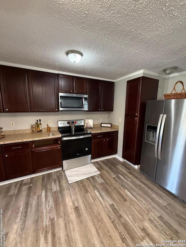 kitchen featuring dark brown cabinets, appliances with stainless steel finishes, light hardwood / wood-style flooring, and a textured ceiling