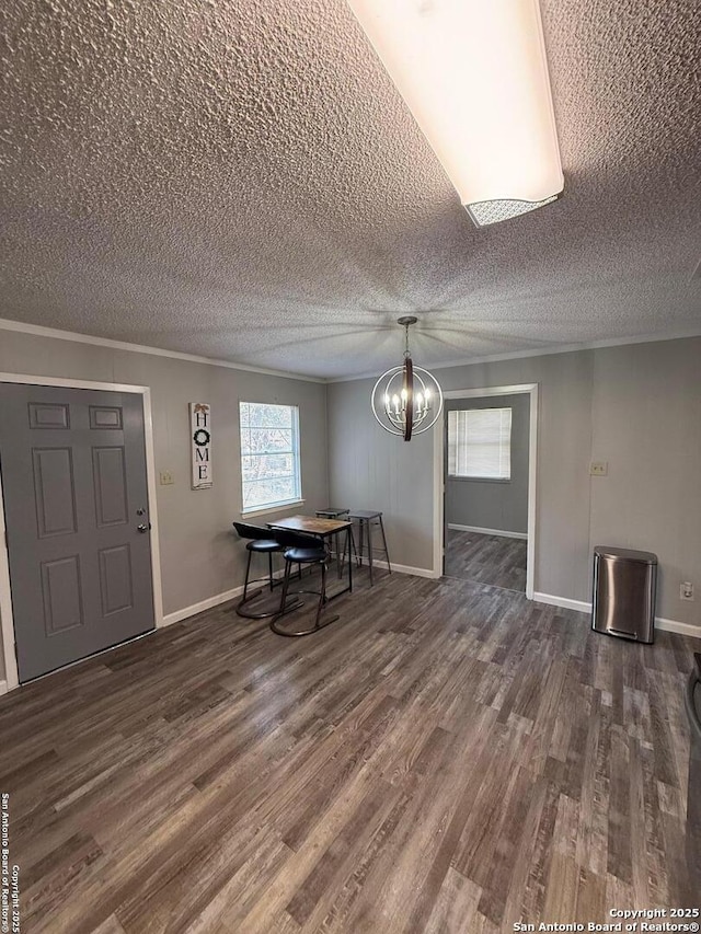 unfurnished dining area with a notable chandelier, crown molding, dark wood-type flooring, and a textured ceiling