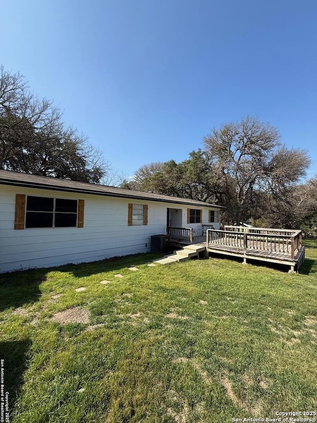 back of property with a wooden deck, a lawn, and central air condition unit