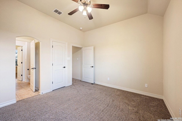 unfurnished bedroom with ceiling fan, vaulted ceiling, light colored carpet, and ensuite bathroom