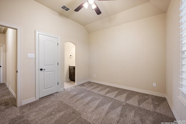 unfurnished bedroom featuring carpet, vaulted ceiling, ensuite bath, and ceiling fan