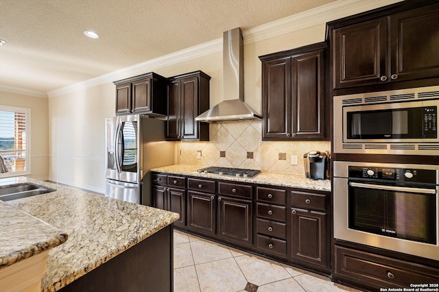 kitchen with appliances with stainless steel finishes, sink, light tile patterned floors, wall chimney exhaust hood, and decorative backsplash