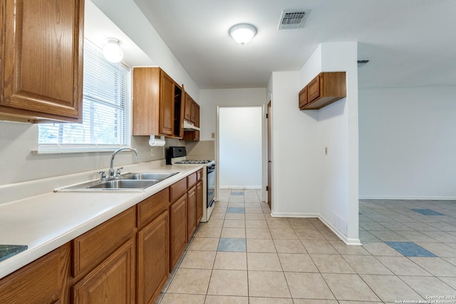 kitchen with range with gas stovetop, sink, and light tile patterned floors