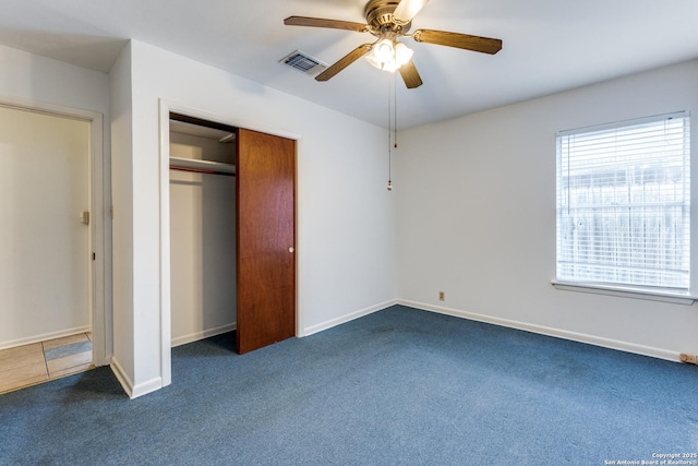 unfurnished bedroom featuring dark colored carpet, ceiling fan, and a closet