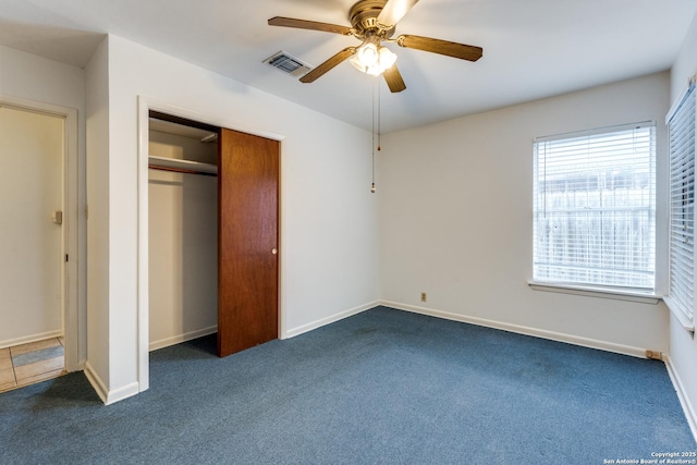 unfurnished bedroom featuring ceiling fan, a closet, and dark colored carpet