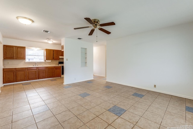 unfurnished living room with sink, light tile patterned floors, and ceiling fan