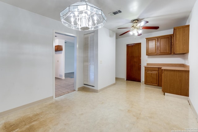 unfurnished dining area with ceiling fan with notable chandelier