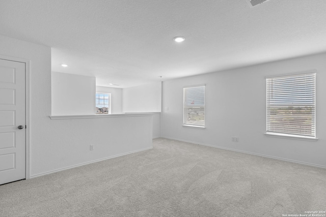 carpeted empty room with a textured ceiling