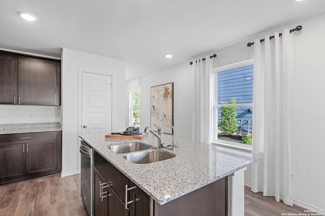 kitchen with an island with sink, dark brown cabinets, and sink