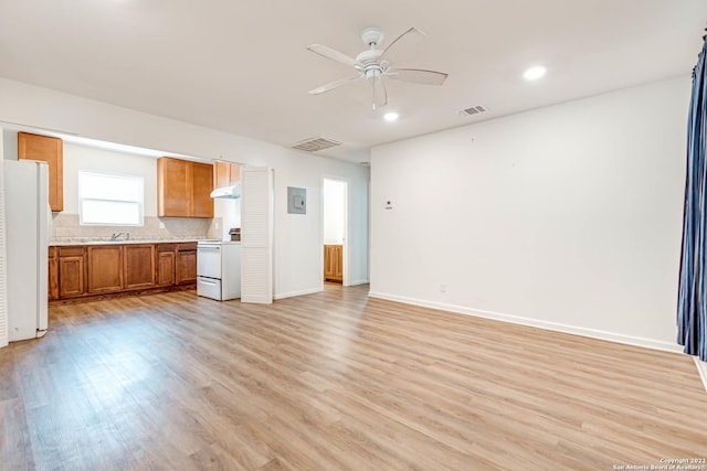 unfurnished living room featuring ceiling fan, electric panel, and light wood-type flooring