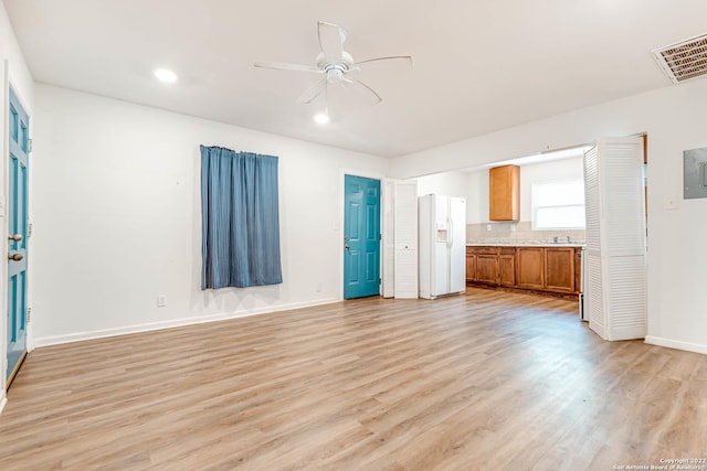 unfurnished living room featuring light hardwood / wood-style floors, ceiling fan, and electric panel