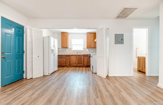 kitchen with white appliances, electric panel, light hardwood / wood-style flooring, and backsplash