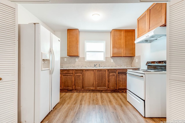 kitchen with sink, white appliances, light hardwood / wood-style floors, and backsplash