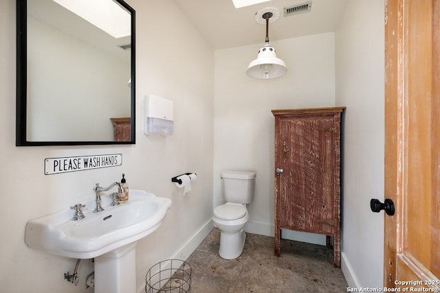 bathroom with sink, a skylight, and toilet