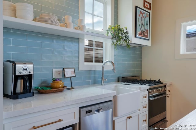 kitchen featuring white cabinetry, light stone countertops, decorative backsplash, and stainless steel appliances